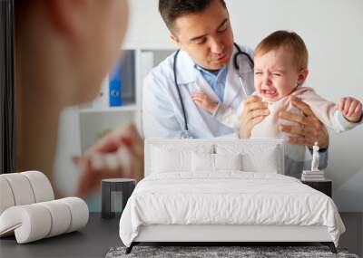 doctor or pediatrician with crying baby at clinic Wall mural