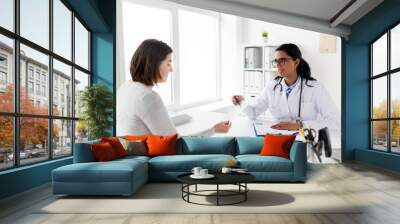 doctor with clipboard and woman patient at clinic Wall mural