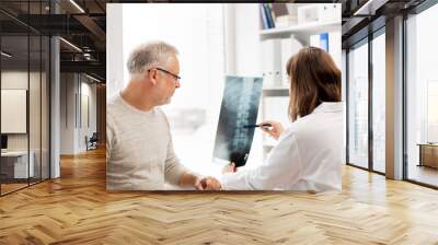 doctor with spine x-ray and senior man at hospital Wall mural