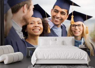 education, graduation and people concept - group of happy international students in mortar boards and bachelor gowns outdoors Wall mural