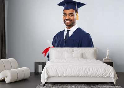 education, graduation and people concept - happy smiling indian male graduate student in mortar board and bachelor gown with diploma over grey background Wall mural