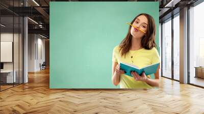 education, school and people concept - teenage student girl in yellow t-shirt with diary or notebook and pencil-mustache over green chalk board background Wall mural