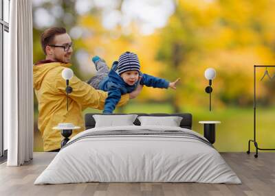 family, childhood and fatherhood concept - happy father and little son playing and having fun outdoors over autumn park background Wall mural