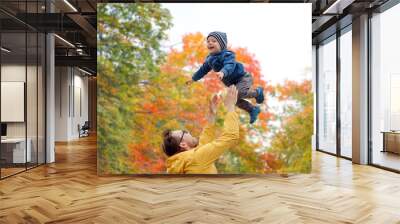 family, childhood and fatherhood concept - happy father and little son playing and having fun outdoors over autumn park background Wall mural