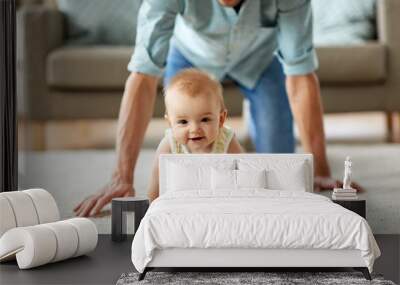 family, fatherhood and parenthood concept - happy little baby girl with father at home crawling on floor Wall mural