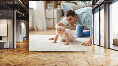 family, fatherhood and parenthood concept - happy little baby girl with father at home crawling on floor Wall mural