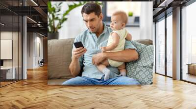 family, fatherhood and technology concept - father with little baby daughter using smartphone at home Wall mural