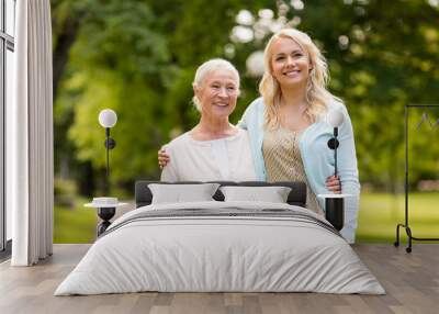 family, generation and people concept - happy smiling young daughter with senior mother hugging at summer park Wall mural