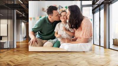 family, holidays and people concept - portrait of happy mother and father kissing little son sitting on sofa at home party Wall mural