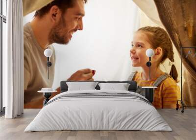 family, hygge and people concept - happy father and little daughter playing tea party in kids tent at night at home Wall mural