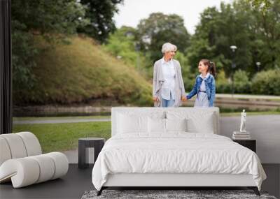 family, leisure and people concept - happy grandmother and granddaughter walking at summer park Wall mural