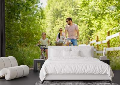 family, leisure and people concept - happy mother, father and little daughter riding bicycles in summer park Wall mural