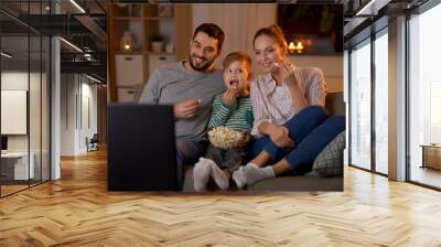 family, leisure and people concept - happy smiling father, mother and little son eating popcorn and watching tv at home in evening Wall mural