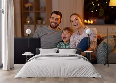 family, leisure and people concept - happy smiling father, mother and little son with remote control watching tv at home at night Wall mural