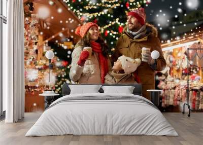 family, winter holidays and celebration concept - happy mother, father and little daughter with takeaway drinks at christmas market on town hall square in tallinn, estonia over snow Wall mural