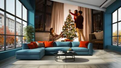 family, winter holidays and people concept - happy mother, father and little daughter decorating christmas tree at home Wall mural