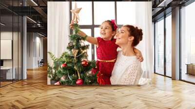 family, winter holidays and people concept - happy mother and little daughter decorating christmas tree at home Wall mural