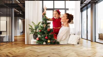 family, winter holidays and people concept - happy mother and little daughter decorating christmas tree at home Wall mural