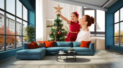 family, winter holidays and people concept - happy mother and little daughter decorating christmas tree at home Wall mural