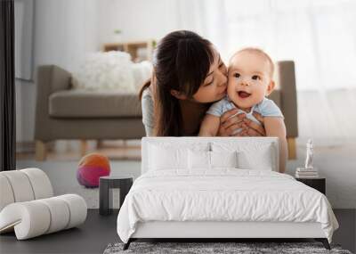 family and motherhood concept - happy smiling young asian mother kissing little baby at home Wall mural