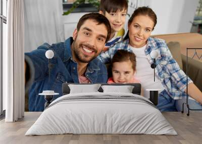 family and people concept - happy father, mother, little son and daughter taking selfie at home Wall mural