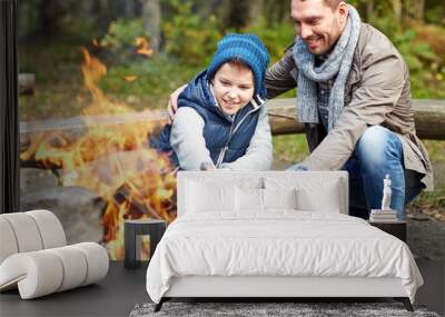 father and son roasting marshmallow over campfire Wall mural