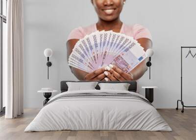 finance, currency and people concept - happy african american young woman holding euro money banknotes over grey background Wall mural