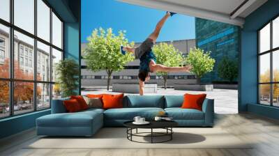 fitness, sport, training and lifestyle concept - young man exercising and doing handstand on one arm outdoors Wall mural