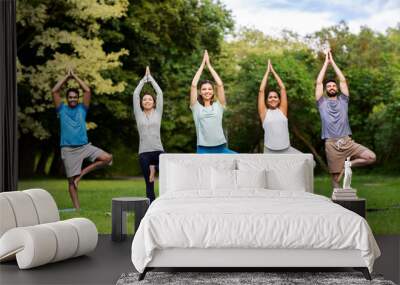 fitness, sport and healthy lifestyle concept - group of happy people doing yoga at summer park Wall mural