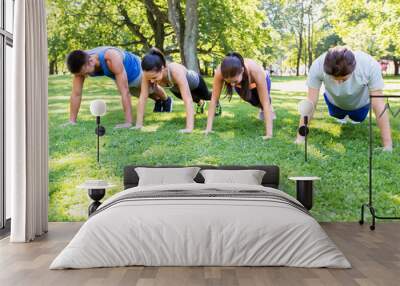 fitness, sport and healthy lifestyle concept - group of people doing push-ups or plank exercise at summer park or boot camp Wall mural