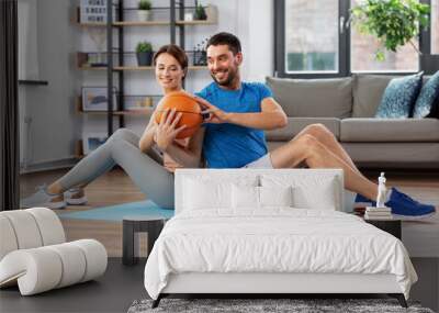 fitness, sport and healthy lifestyle concept - happy couple exercising with ball at home Wall mural