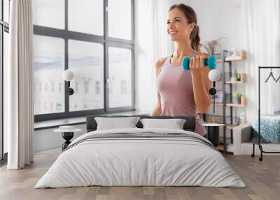 fitness, sport and healthy lifestyle concept - smiling young woman with dumbbells exercising at home Wall mural