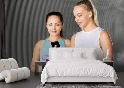 fitness, sport and healthy lifestyle concept - smiling young women or female friends with smartphone and flask Wall mural