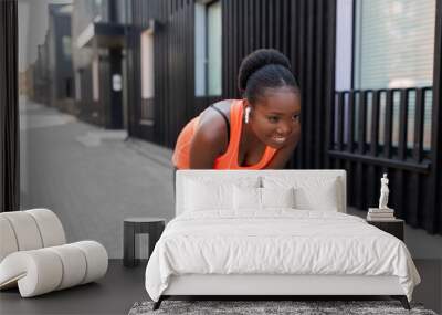 fitness, sport and technology concept - happy smiling young african american woman with wireless earphones exercising in city Wall mural