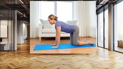 fitness, yoga and healthy lifestyle concept - woman doing cow pose on mats at home Wall mural