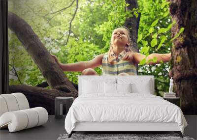 friendship, childhood, leisure and people concept - happy girl climbing up tree and having fun in summer park Wall mural