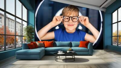 future technology, virtual reality and vision concept - happy smiling boy in glasses over white illumination in dark room Wall mural