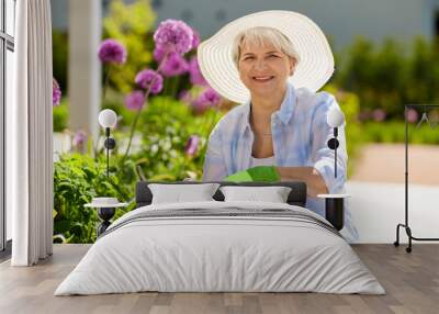 gardening and people concept - happy senior woman with pruner taking care of flowers at summer garden Wall mural