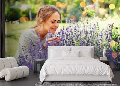 gardening and people concept - happy young woman smelling lavender flowers at summer garden over festive lights background Wall mural