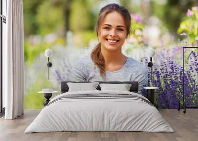 gardening and people concept - happy young woman with flowers at summer garden Wall mural