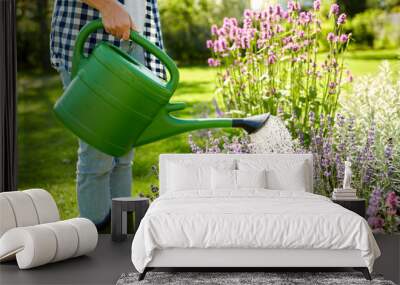 gardening and people concept - young woman with watering can pouring water to flowers at garden Wall mural