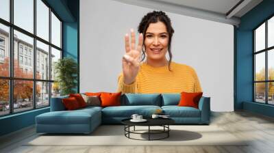 gesture, count and people concept - happy smiling woman in pullover showing three fingers over grey background Wall mural