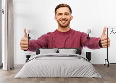 gesture and people concept - happy young man showing thumbs up over white background Wall mural