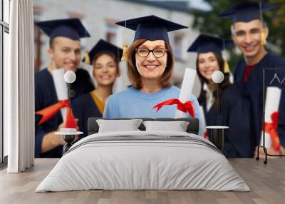 graduation, education and old age concept - happy senior graduate student woman in mortar board with diploma next to young people over university campus background Wall mural