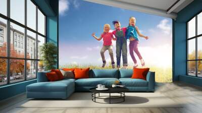 group of happy kids jumping high on green field Wall mural