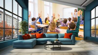 group of school kids raising hands in classroom Wall mural