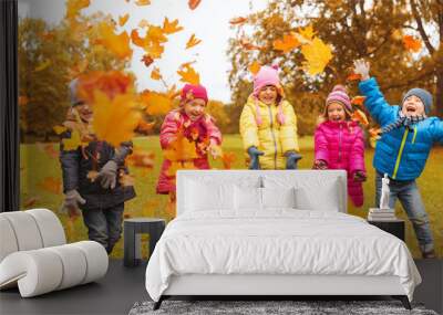 happy children playing with autumn leaves in park Wall mural