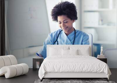 happy female doctor or nurse writing to clipboard Wall mural