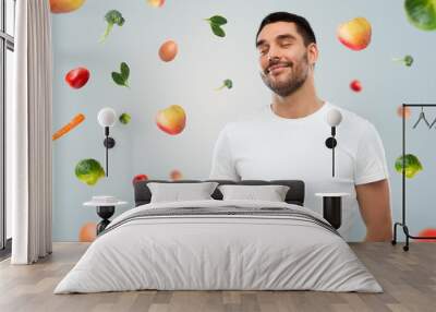 happy full man touching tummy over falling fruits Wall mural