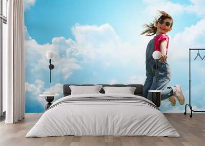 happy little girl jumping high over blue sky Wall mural